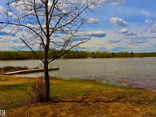 Waterfront property featuring a private dock, natural shoreline, and mature trees - #26 5508 Twp Rd 593A, Rural Barrhead County, AB - Outdoor With Body Of Water With View