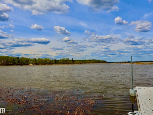 Waterfront property featuring a dock system, natural shoreline, and distant tree line - #26 5508 Twp Rd 593A, Rural Barrhead County, AB - Outdoor With Body Of Water With View
