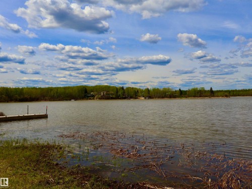 Waterfront expanse featuring a dock, natural shoreline, and distant treeline - #26 5508 Twp Rd 593A, Rural Barrhead County, AB - Outdoor With Body Of Water With View