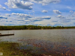 Waterfront expanse featuring a dock, natural shoreline, and distant treeline - 