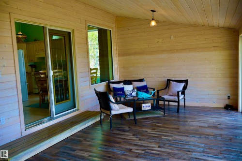 Covered porch featuring wood-finish flooring, natural wood plank walls, and a matching wood plank ceiling - #26 5508 Twp Rd 593A, Rural Barrhead County, AB - Outdoor With Deck Patio Veranda With Exterior