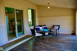 Covered porch featuring wood-finish flooring, natural wood plank walls, and a matching wood plank ceiling - 