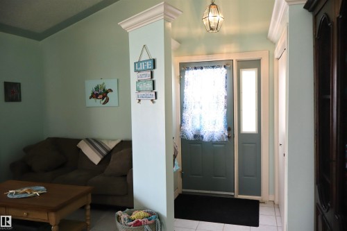 Entryway featuring a paneled door with a side light, white tile flooring, and a decorative overhead light fixture - #26 5508 Twp Rd 593A, Rural Barrhead County, AB - Indoor Photo Showing Other Room