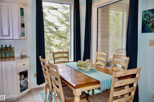 Dining area featuring a wood-finish table, tile flooring, and light blue wall paint - #26 5508 Twp Rd 593A, Rural Barrhead County, AB - Indoor Photo Showing Dining Room