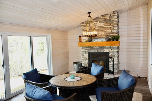 Vaulted shiplap ceiling over a stone fireplace with a substantial wood mantel - #26 5508 Twp Rd 593A, Rural Barrhead County, AB - Indoor With Fireplace