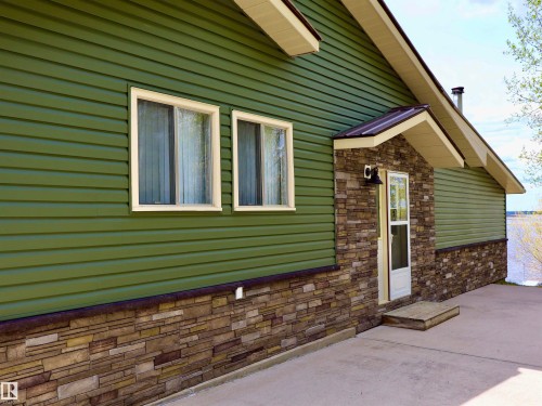 Green horizontal siding exterior with a stacked stone facade - #26 5508 Twp Rd 593A, Rural Barrhead County, AB - Outdoor With Exterior