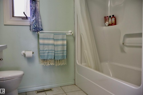 Bathroom featuring a white bathtub, integrated shower shelving, and a toilet - #26 5508 Twp Rd 593A, Rural Barrhead County, AB - Indoor Photo Showing Bathroom