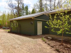 Detached garage with dark green horizontal siding, white trim, and a metal roof - 