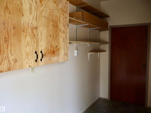 Storage space featuring a light wood cabinet with black hardware and built-in shelving - #26 5508 Twp Rd 593A, Rural Barrhead County, AB - Indoor Photo Showing Other Room