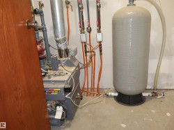 Utility area featuring a water heater, boiler system, exposed plumbing, and concrete flooring - 