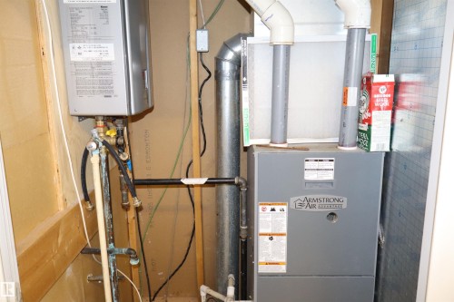 Utility area featuring a wall-mounted water heater and an Armstrong Air furnace unit - #26 5508 Twp Rd 593A, Rural Barrhead County, AB - Indoor Photo Showing Basement