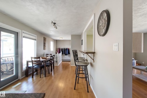 Open-concept dining area featuring wood-finish flooring, a wall-mounted breakfast bar, and track lighting - 803 12 Avenue, Cold Lake, AB - Indoor Photo Showing Dining Room