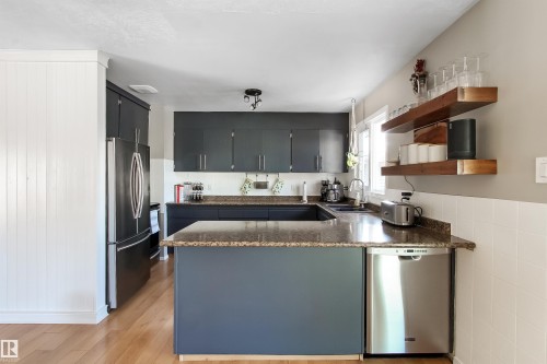 U-shaped kitchen featuring wood-finish flooring, dark cabinetry, light-toned countertops, and open wooden shelving - 803 12 Avenue, Cold Lake, AB - Indoor Photo Showing Kitchen