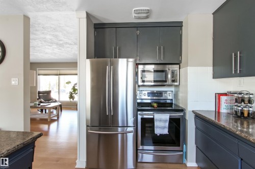 Kitchen featuring stainless steel appliances, dark cabinetry, and stone-finish countertops - 803 12 Avenue, Cold Lake, AB - Indoor Photo Showing Kitchen
