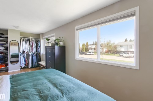 Bedroom featuring a large double window with white trim, a built-in closet system with hanging rods and shelving, and light-toned flooring - 803 12 Avenue, Cold Lake, AB - Indoor Photo Showing Bedroom