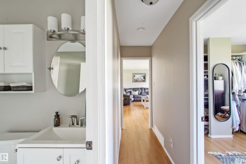Bathroom featuring a rectangular sink, vanity with white shaker-style cabinetry, oval mirror, and a three-light fixture - 803 12 Avenue, Cold Lake, AB - Indoor Photo Showing Laundry Room
