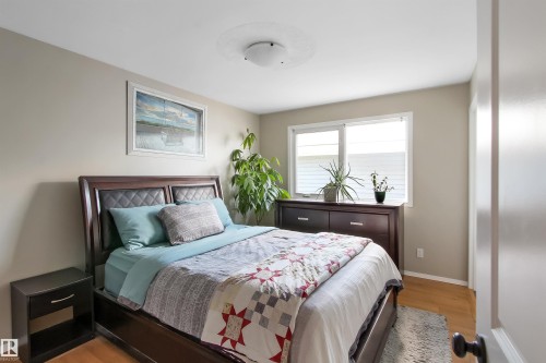 Bedroom featuring light wood-finish flooring, neutral wall paint, and a large window with white trim - 803 12 Avenue, Cold Lake, AB - Indoor Photo Showing Bedroom