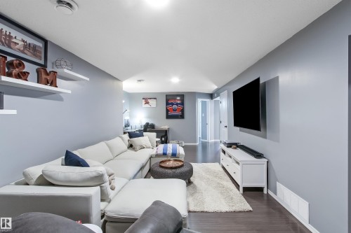 Spacious recreation area featuring wood-finish flooring, light gray walls, white ceiling, and built-in floating wall shelves - 803 12 Avenue, Cold Lake, AB - Indoor