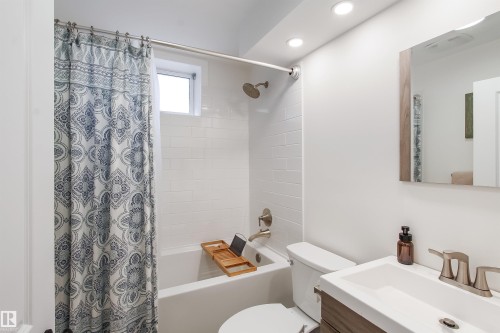 Contemporary bathroom featuring a subway-tiled shower, brushed nickel fixtures, recessed lighting, a modern vanity with integrated sink, and a framed mirror - 803 12 Avenue, Cold Lake, AB - Indoor Photo Showing Bathroom