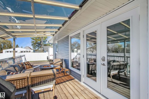 Expansive wooden deck featuring a clear panel overhead cover, white trim, and light gray siding - 803 12 Avenue, Cold Lake, AB - Outdoor With Deck Patio Veranda