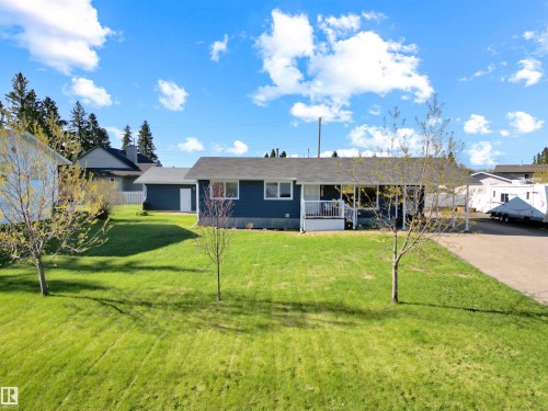 Blue exterior with white trim, featuring a dark shingle roof and a concrete driveway - 803 12 Avenue, Cold Lake, AB - Outdoor