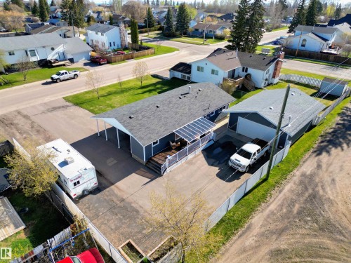 Dark gray siding exterior featuring a white trim garage door, covered porch, and asphalt driveway - 803 12 Avenue, Cold Lake, AB - Outdoor With View