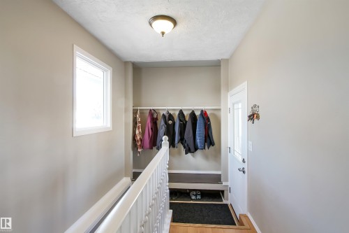 Entryway with a white paneled door featuring decorative glass inserts, wood-finish flooring, and a white spindle railing - 803 12 Avenue, Cold Lake, AB - Indoor Photo Showing Other Room