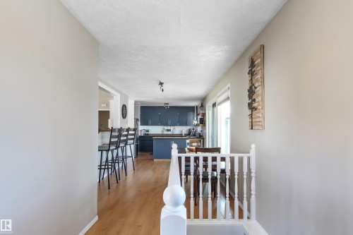 White balustrade railing with wood-finish flooring extending into the kitchen and dining areas - 803 12 Avenue, Cold Lake, AB - Indoor Photo Showing Other Room