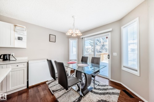 Dining area featuring wood-finish flooring, a white paneled lower cabinet, light-toned walls, a glass patio door, and a vertical window with blinds - 19024 50 Avenue, Edmonton, AB - Indoor Photo Showing Dining Room