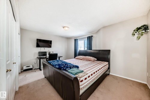 Carpeted bedroom featuring a large window with privacy coverings, light-toned walls, and a ceiling-mounted light fixture - 19024 50 Avenue, Edmonton, AB - Indoor Photo Showing Bedroom