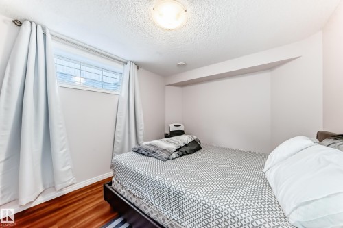 Bedroom featuring wood-finish flooring, a single window with blinds, and white curtains - 19024 50 Avenue, Edmonton, AB - Indoor Photo Showing Bedroom