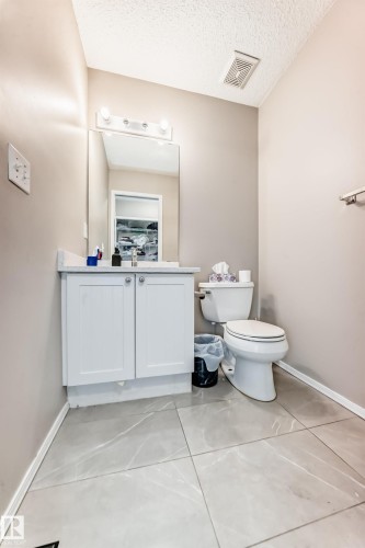 Vanity with white shaker-style cabinetry, a light-toned countertop, and a rectangular mirror - 19024 50 Avenue, Edmonton, AB - Indoor Photo Showing Bathroom