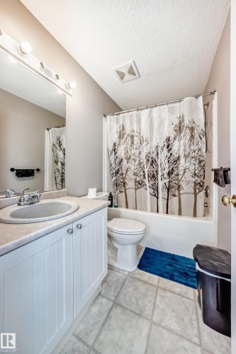 Bathroom featuring a vanity with a drop-in sink, a shower-tub combination with a shower curtain, and a standard toilet - 19024 50 Avenue, Edmonton, AB - Indoor Photo Showing Bathroom