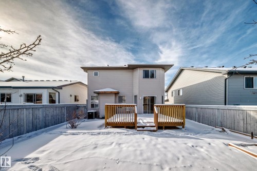 Rear exterior featuring a wood-plank deck with railing, light-colored horizontal siding, and multiple windows - 19024 50 Avenue, Edmonton, AB - Outdoor With Exterior