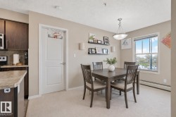 Dining area featuring light carpeting, neutral wall tones, and a window with natural light - 
