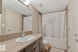 Bathroom featuring a wood-finish vanity with an integrated sink, stone-look countertop, and chrome faucet - 