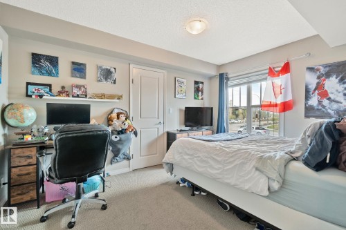 Bedroom featuring carpet flooring, a large window with horizontal blinds, a neutral wall color, a built-in overhead light fixture, and a white interior door - 206 103 Ambleside Drive, Edmonton, AB - Indoor