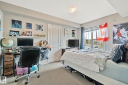 Bedroom featuring carpet flooring, a large window with horizontal blinds, a neutral wall color, a built-in overhead light fixture, and a white interior door - 