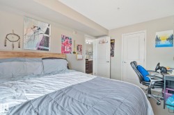 Bedroom featuring a light wood-finish headboard and neutral wall color - 