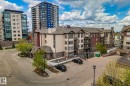 Multi-level building with stone and siding facade, private balconies, and an adjacent surface parking area - 206 103 Ambleside Drive, Edmonton, AB  - Outdoor With Balcony With Facade 