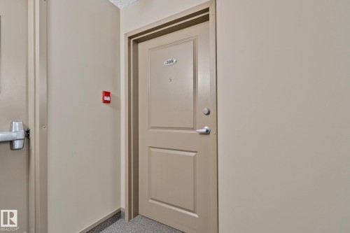 Entry door with panel detailing and silver-toned hardware - 206 103 Ambleside Drive, Edmonton, AB - Indoor Photo Showing Other Room