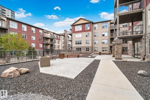 Modern building exterior featuring red and beige siding, stone accents, and multiple balconies - 206 103 Ambleside Drive, Edmonton, AB - Outdoor With Balcony With Facade