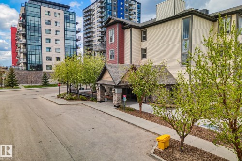 Multi-story building featuring a prominent stone and shingle entry canopy - 206 103 Ambleside Drive, Edmonton, AB - Outdoor With Facade