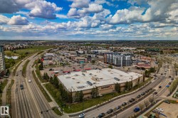 Aerial perspective of a commercial district featuring a large grocery store, multiple retail buildings, a gas station, and a multi-lane roadway - 