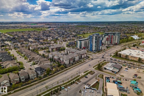 Expansive aerial view showcasing a mixed-use district with residential homes, multi-story apartment buildings, commercial structures, and dedicated road infrastructure - 206 103 Ambleside Drive, Edmonton, AB - Outdoor With View