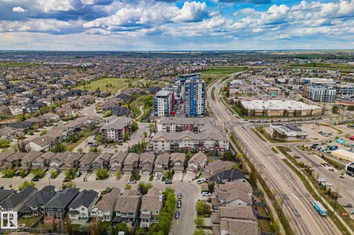 Aerial perspective showcasing a residential community with varied architectural styles, a commercial district, and a multi-lane roadway - 206 103 Ambleside Drive, Edmonton, AB - Outdoor With View