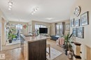 Open-concept living area featuring a kitchen island with dual sinks, overhead track lighting, beige carpeting, and multiple windows providing natural light - 206 103 Ambleside Drive, Edmonton, AB  - Indoor 