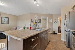 Kitchen island featuring a double basin sink, stone-finish countertop, and dark wood-finish cabinetry with stainless steel hardware - 