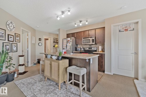 Kitchen featuring dark wood-finish cabinetry, stainless steel appliances, and track lighting - 206 103 Ambleside Drive, Edmonton, AB - Indoor Photo Showing Kitchen