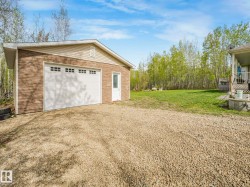 Detached garage featuring brick-patterned siding, vinyl siding gables, an overhead door with window inserts, and an entry door with a glass panel - 